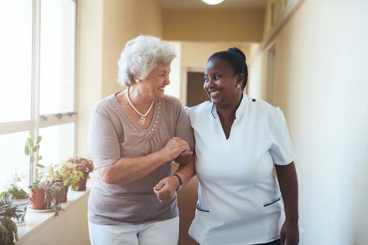 Nurse walking with elder woman with joy